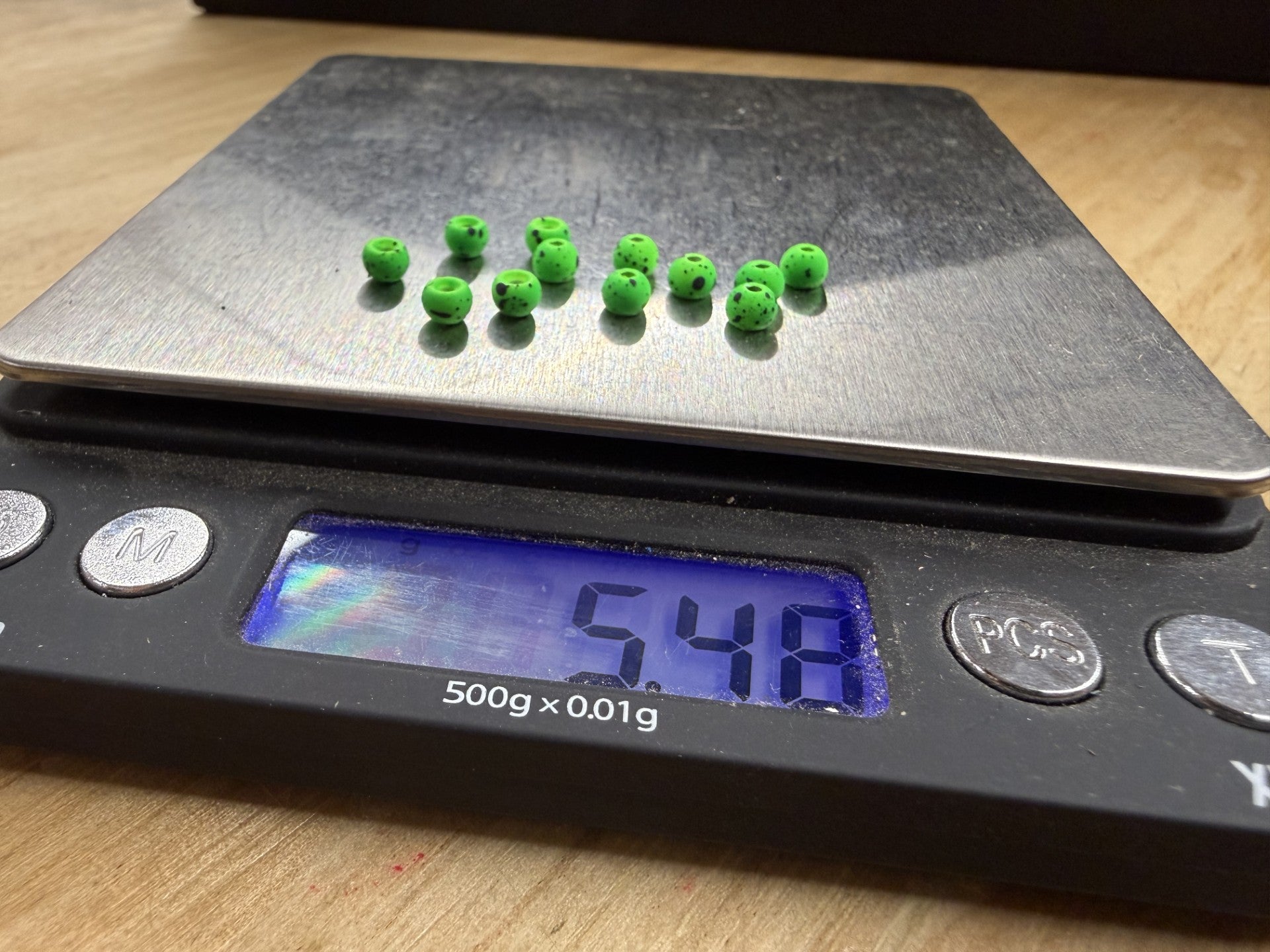 Twelve Firehole 4.0mm Round Stones in Kiwi on a digital scale reading 5.48 grams